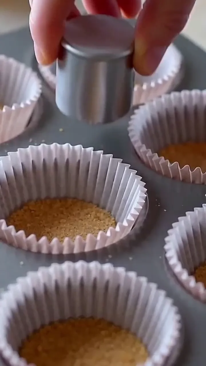 Graham cracker crust pressed into lined muffin cups